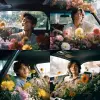 18 year old handsome Korean male model sat in the car, smiling, surrounded by flowers, art by Rinko kawauchi, in the style of naturalisticposes, low angle, youthful energy, bodyextentions, analog film