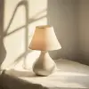 极简主义的白色陶瓷底座，80 mm f/1.7，在柔和自然的窗户光的映衬下展示灯