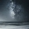 海滩上洒满星空，前方是深灰色的沙子和浅水，海平面上方可以看到银河，在夜色下形成了无尽的广阔视野。就像一个人呆在家里一样，广阔的海洋为场景增添了神秘感。黑色背景凸显细节，高对比度使一切更加生动。，真实感，--ar 59：128