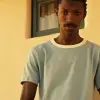 这张复古照片是一位英俊的黑人男子穿着白色和红色运动短裤，拍摄于2034年，拍摄于威斯康星州的一所大学。5英尺的广角镜头描绘了芬兰汤姆的风格--c 50 --ar 61：128 --v 5.2 --风格的原始