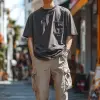 照片，时尚杂志封面，34岁男模特站立，自信的姿势，穿着纯深灰色过度贴合T恤和深米色货物慢跑裤，耐克运动鞋，俏皮的外观，完美的身材比例，一手拿着冰淇淋，吃着冰淇淋，嘴巴被遮住，看不到标志或品牌，场景捕捉到街头服饰轻松轻松的风格，摄影工作室氛围，相机设置确保模型成为焦点，使用f/8中等口径的自然光设置来平衡焦点和细节，UHD，丰富的细节--ar 9：16 --style raw --styminste