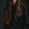 照片，全身，年轻男子职业模特姿势，极简时尚，时尚的nessy长发，凝视，二手相机是佳能EOS R5，配备RF 85毫米F1.2L镜头，纯深灰色环境，现实主义工作室灯光设置，琴键灯，UHD，丰富的细节--ar 9：16 --风格原始