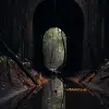 隧道入口处悬挂着一块木板，风格为黑暗、喜怒无常的风景、澳大利亚风景、后处理、traincore、冒险主题、黑暗反射、南方哥特式风格--ar 85：128 --v 5.2