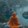 一位身穿橙色长袍的僧人坐在水边，风格为凯西·韦尔顿、本·templesmith、色彩缤纷的湍流、dao trong le、深青色和栗色、高分辨率、古泰群--ar 24：35 --styleum 750 --v 6