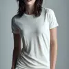 女时装模特站立，穿着纯白T恤和白色短裤，姿势休闲，双手在外面放松，中性灰色背景，全身，极简主义工作室灯光   --ar 9：16 --c20