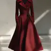 冬季商务宴请，女士酒红色毛呢外套加黑色长靴，深色调突出，沉稳优雅风格，外套下摆厚实，室内暖灯光反射细腻光影，服饰设计效果图     --ar 9:16