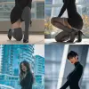 一名女子身穿黑色长袖紧身连衣裙，穿着灰色高大腿丝袜和黑色漆皮高跟鞋，蹲在以现代建筑为背景的城市户外环境中，呈现出逼真的风格，高度注重服装和配饰的细节   --ar 25：44